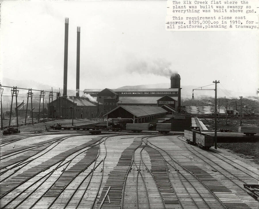 A photograph of the Elk River sawmill and information regarding the Elk Creek flat where the plant was built and how it was so swampy that there was a $125,000.00 cost in 1910 to build the platforms, planking, and tramways above ground.