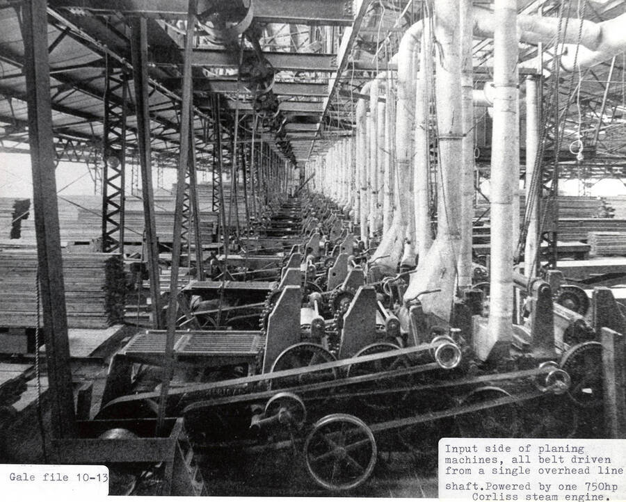 A photograph of the input side of belt driven planing machines from a single overhead line shaft. They were powered by one 750hp Corliss steam engine.