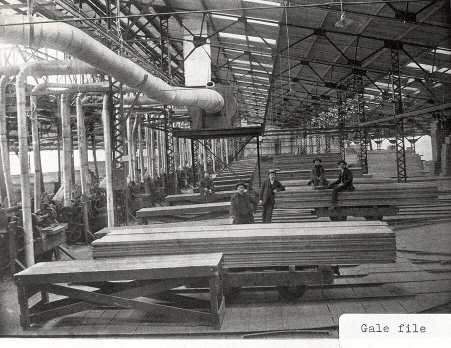 A photograph of employees and lumber at the sawmill.