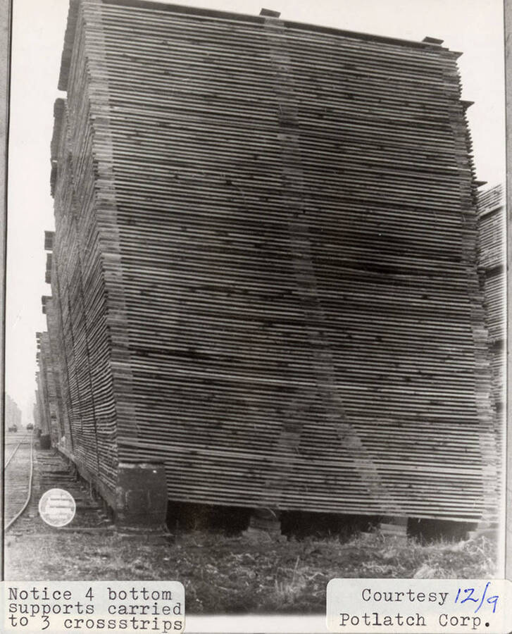 A photograph of a stack of lumber with four bottom supports carried to three cross strips.