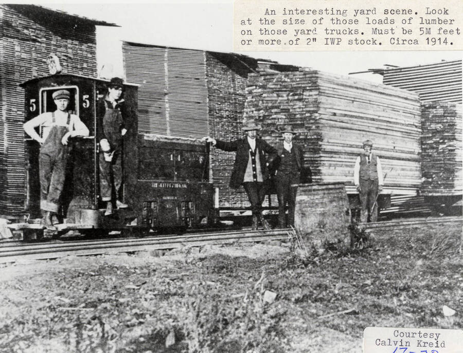 A photograph of workers on yard trucks with very large stacks of lumber (approximately 5M feet of 2' Idaho White Pine stock).