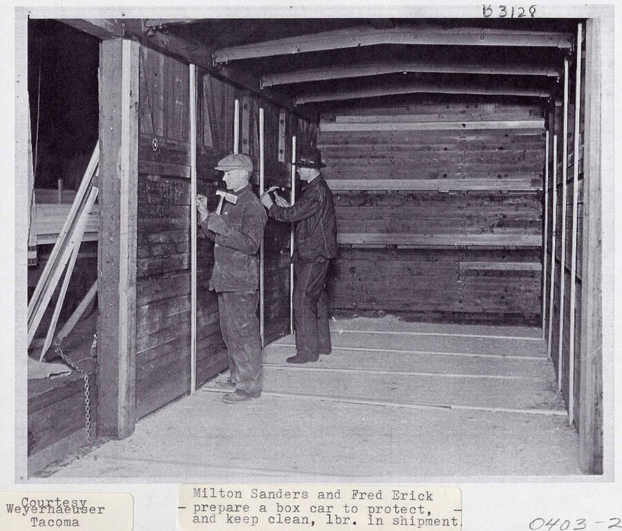 A photograph of Milton Sanders and Fred Erick prepare a box car so lumber is clean and protected during shipment.