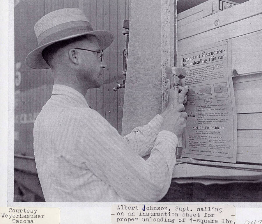 A photograph of superintendent Alber Johnson nailing an instruction sheet for proper unloading to the 4-Square lumber.