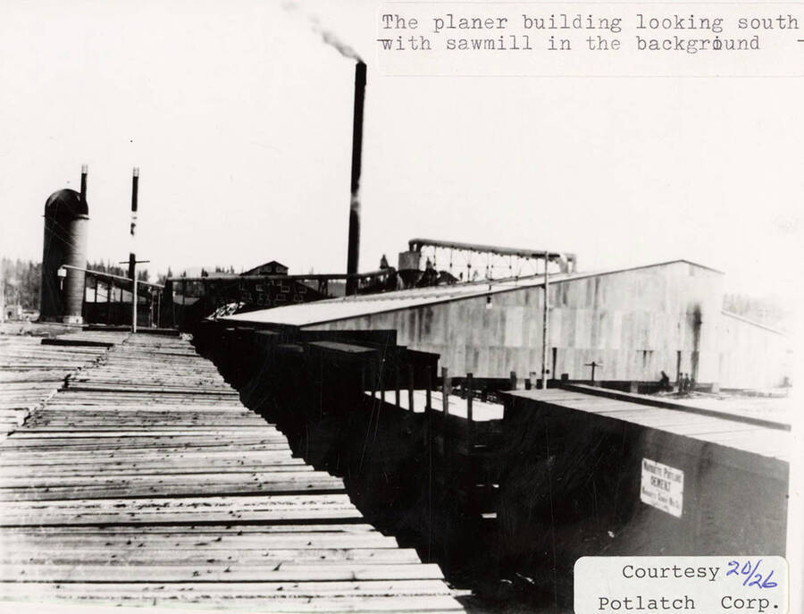 A photograph of a south view of the planer building with a sawmill in the background.