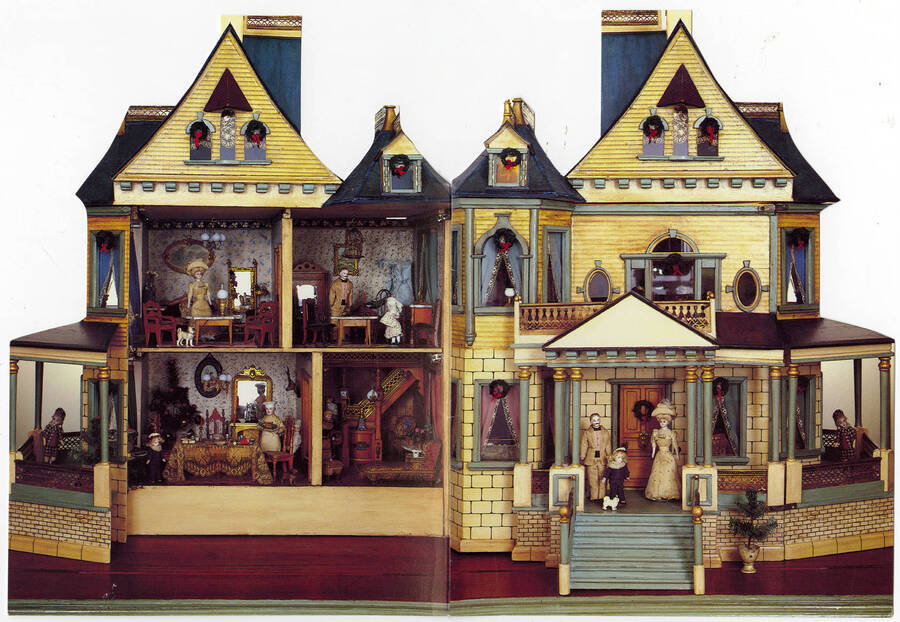 A photograph of the front of a holiday card. The card is of a very detailed doll house with several rooms and dolls.