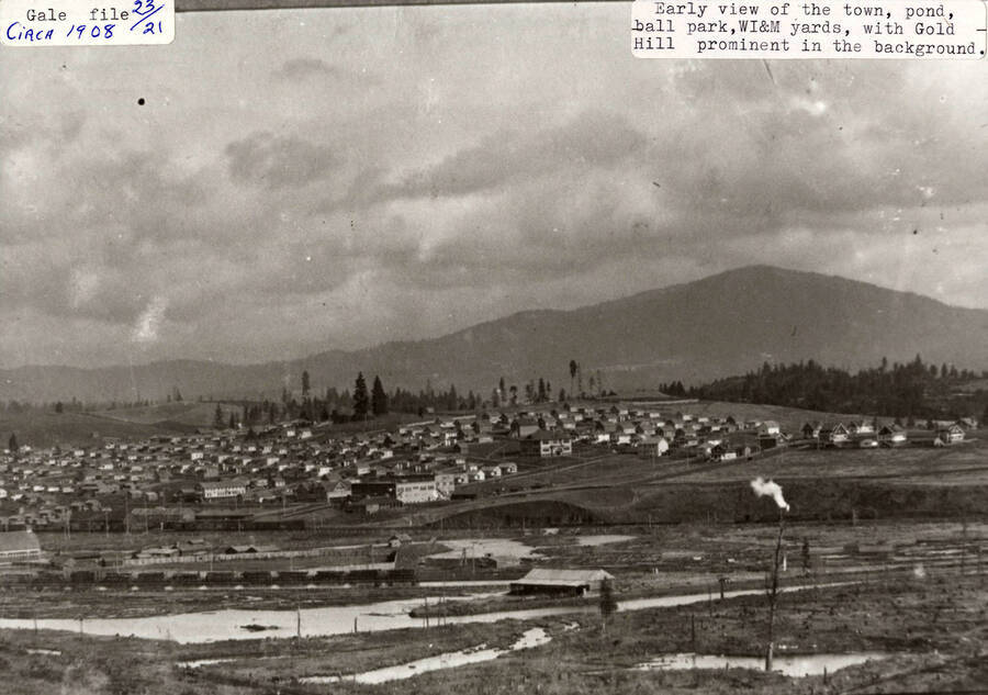 A photograph of Potlatch, Idaho with the view of the town, pond, ball park, WI&M yards, and Gold Hill in the background.