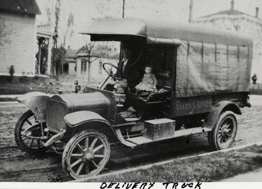 A man driving an Allen & Lewis delivery truck with a young girl.