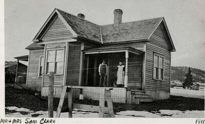 Mr. and Mrs. Sam Clark posing for a photograph on the front porch of a house. The photograph was taken in 1911.