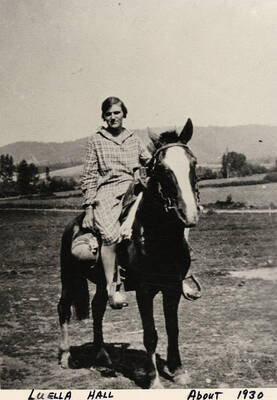 Luella Hall riding a horse in a field. Photograph taken about 1930.