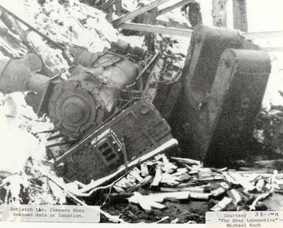 Company Shay locomotive knocked off the tracks. The engine appears to be tipped over on its side.