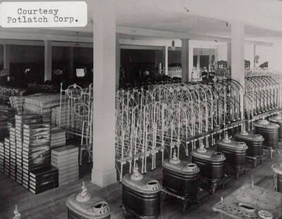 A photograph of the interior of a warehouse with what appears to be bed frames, mattresses, and furnaces.