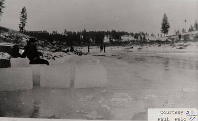 A photograph of ice blocks, people, and pools of ice.