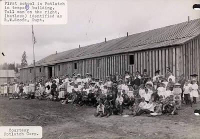 A photograph of the students and temporary building of the first school in Potlatch, Idaho. The Superintendent R. W. Scofe has been identified as the tall man on the right without a hat.