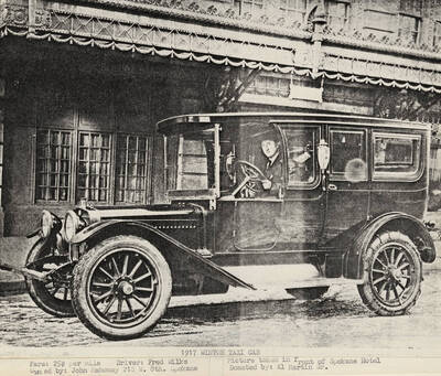 Fred Wilks behind the wheel of the Winton Taxi cab while it is parked in front of the Spokane Hotel. In 1917 the taxi cab's owner was John Mahoeny and the fare was 25 cents per mile.