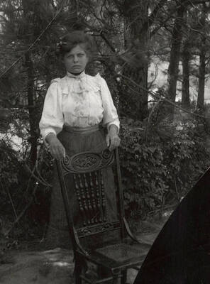 A photograph of an unknown woman with a chair.