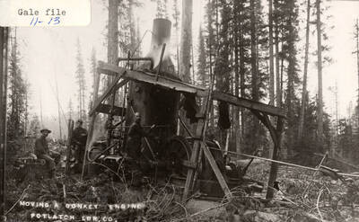 A few men moving a steam donkey engine.