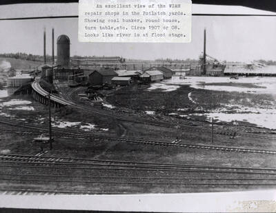 View of the WI&M repair shops in the Potlatch yards. The view shows the coal bunker, the round house, and the turn table. The river can also be seen at flood stage.