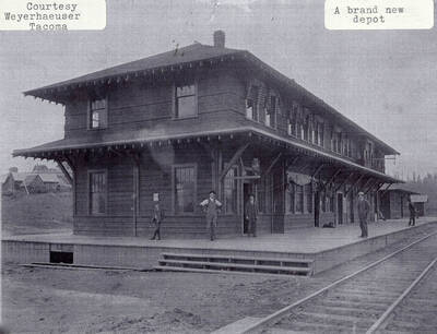 The brand new depot. People can be seen standing on the deck of the new building and curtains can be seen hanging from the windows.