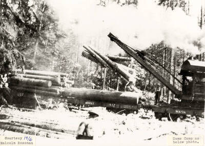 Men using a jammer to load logs onto flat cars.