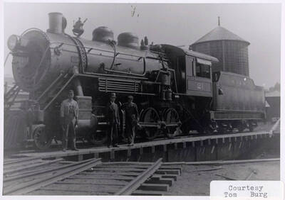 Three men standing next to a No. 21 locomotive.