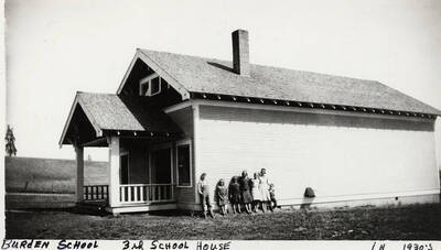 Several students are lined up on the side of the Burden School, 3rd school house. Photograph taken in the 1930's.