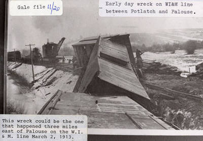 Train wreck on the WI&M line between Potlatch and Palouse. Railroad cars can be seen laying next to the track and men can be seen cleaning up after the wreck.