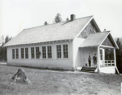 Mountain Gem School. 1/4 mile above Sherman Harrison's homestead. Two people stand on the porch of the school.