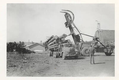 The LeTourneau log unloading machine placing logs into the back of a truck.