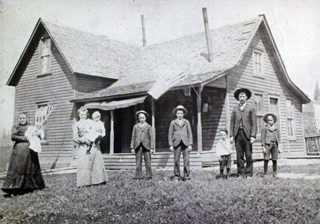 Photograph of the Bircher Family standing in front of their house in Onaway