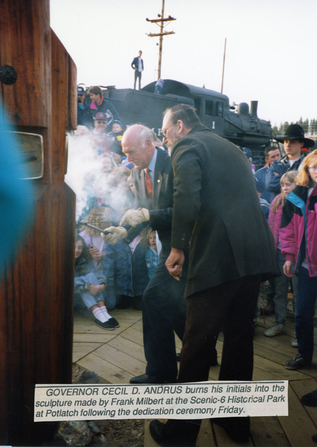 Photograph of Governor Cecil D. Andrus with Frank Milbert burning the governor's initials in the Milbert's sculpture.