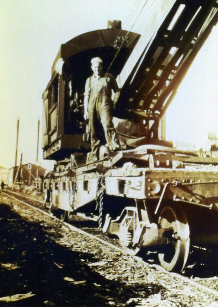 Photograph from slide of a man on a loader with the Potlatch Mill in the background.