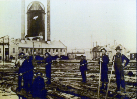 Photograph from slide of men standing on logs on the pond with pike poles at the Potlatch Mill.