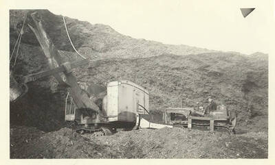 An excavator and an employee on another machine.