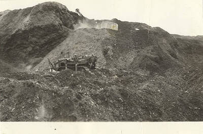 An excavator and other machines changing the landscape of the hill by moving dirt.