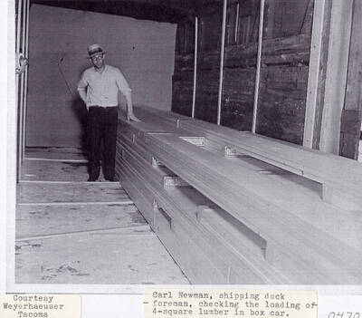 A photograph of shipping dock foreman Carl Newman as he checks the loading of the 4-Square lumber in a box car.