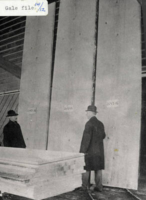 A photograph of two men with slabs of lumber.