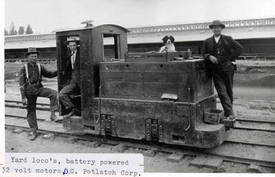 A photograph of employees and dog with the yard loco's battery powered 32 volt motors.