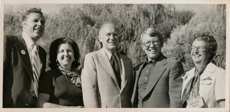 Photo Description: 3 men and 2 women (all democratic officers) are smiling and laughing while posing for a picture. Text back translation "all democrats! Superintend of Public Instruction Roy Truby; Bethine Church; Governor Andrus; Attorney General Tony Park; State Treasurer Marjorie Ruth Moon" Notes read on back "Mindy P-B-6 100 4x3 1/2 Pocatello - Among the luminaries"