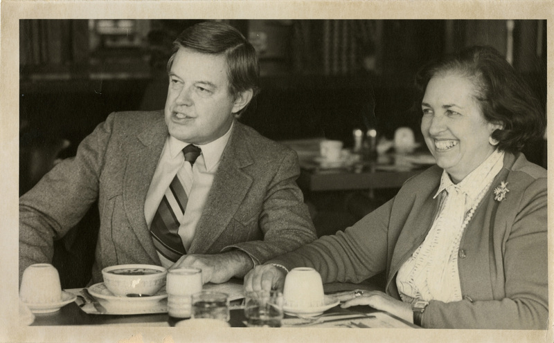 Photo Description: Senator Frank and wife Bethine Church are eating lunch and looking towards the left smiling. Text back translation "Senator Frank & Bethine Church"