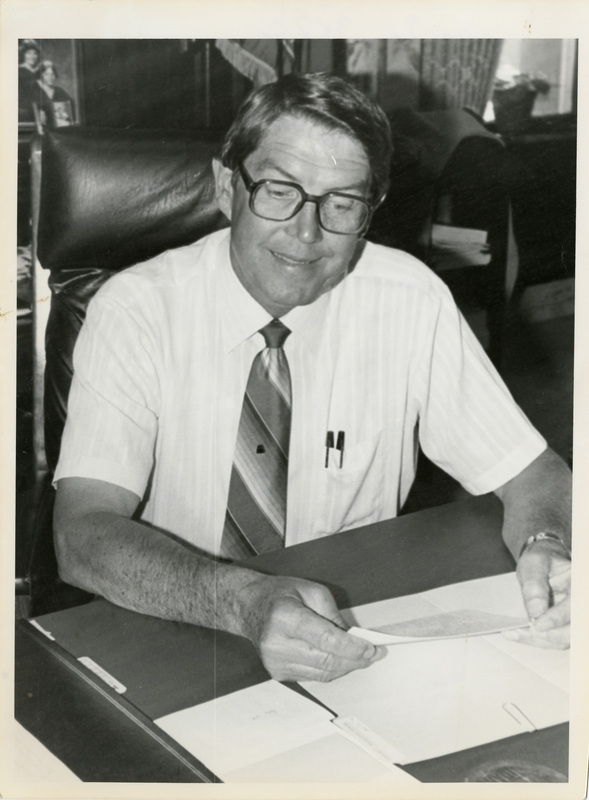 Photo Description: Governor John V Evans is at his desk working on the budget. Notes read on back "100%  3x71/2 Page C-8 Battling the Budget Governor John V Evans"