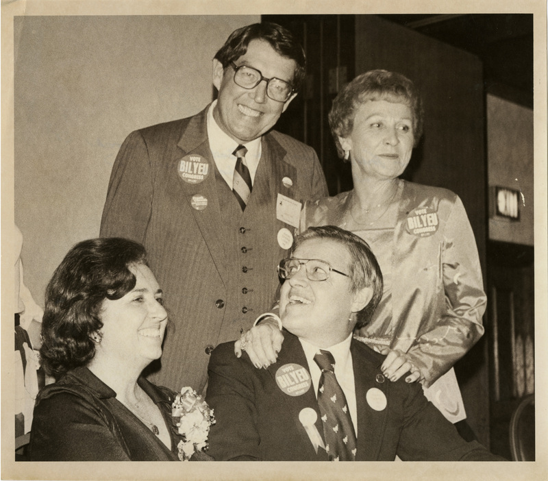 Photo Description: Senator Church (D) and his wife Bethine Church join Governor John Evans (D) and his wife Lola Evans where they wear "Vote BILYEU Congress" stickers as they smile for a picture.