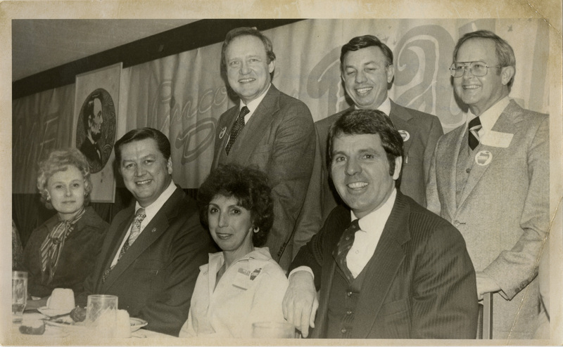 Senator James McClure and Senator Steve Symms join representative George Hansen, Governor Phillip Ball, and republican state chairman Dennis Olsen as they pose for a picture. In addition, Senator Hansens wife,Connie Hansen, and Senator Symms wife, Fran Symms, are also pictured. Text back translation "Idaho's Top Republicans Front Row: Connie & Rep. George Hansen (R), Fran & Senator Steve Symms (R), Back Row: Senator James McClure (R), Republican State Chairman Dennis Olsen, Governor Phillip E. Ball (R)" Notes read on back "100% 4x4 1/2 Page. B-8"