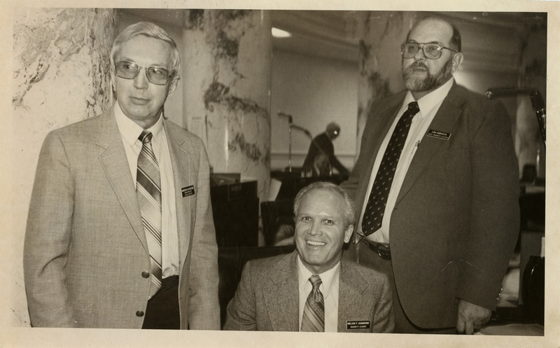 House Democrat Caucus Chairman Marion Davidson, Minority Leader Melvin F. Hammod, and unknown are looking towards the left and smiling at the camera. Text back translation "Eastern Idaho Legislators"