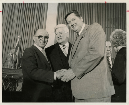 Photo Description: Two men shaking hands with a third person in between them. They're all posing for the photo. Text back translation "Menzchem begin, Prime minister of lsrael 1977 - 1983; Speaker of the House Tip O'neill (D) Speaker 1977-1987; Idaho Congressman George V. Hansen" Notes read on back "3x5 Greets Begin 88 1/2"