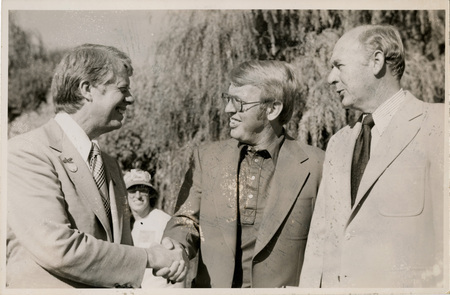 Photo Description: Governor Carter and Attorney General Park are smiling and shaking hands with Governor Andrus (D) right next to them also smiling. Text back translation "Governor Jimmy Carter Attorney General Tony Park Governor Cecil Andrus; this shows Georgia Gov. - Jimmy Cart" Notes read on back "3x3 1/2 Pocatello, Georgia, Gov, lef [crossed out]"