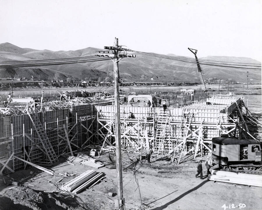 Men work on constructing one of the buildings at the Clearwater Mill. On the right hand side of the photograph sits the cab for one of the cranes. The date written on the photograph is 4/12/1950.