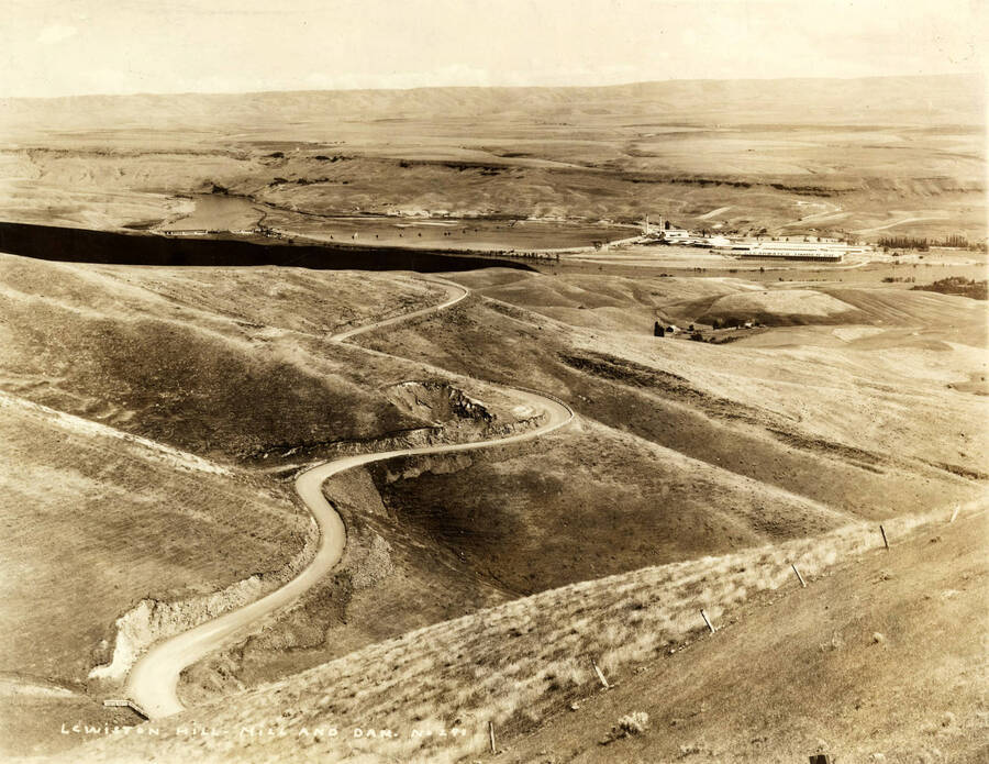 Looking down from Lewiston Hill at the Mill on the right hand side of the photograph. On the left hand side of the photograph is Lewiston Dam and behind it the Clearwater river. Written on the photograph: Lewiston Hill, Mill, and Dam No. 291.