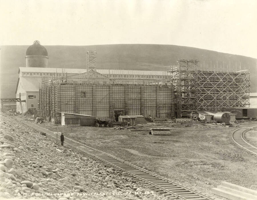 Construction of the fuel house and power plant (description taken from back of the photograph). A worker stands next to a railroad tracks in front of a sign that says 'no Smoking'. Written on the photograph is 'Fuel house and power plant, 3/14/1927 No. 224.'