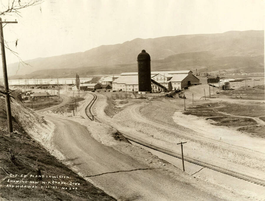 Looking at the Lewiston mill from the start of the log pond. Written on the photograph is 'CT CO Plant Lewiston showing new N. P. erode-dike and highway[sic]. 3/30/1927 No. 240.'
