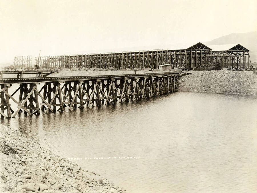 Viewing the rough-dry lumber buildings still under construction. In the center of the photograph is the rail line that goes across the Clearwater river. Written on the photograph is 'Rough dry shed, 5/18/1927, No. 277.'